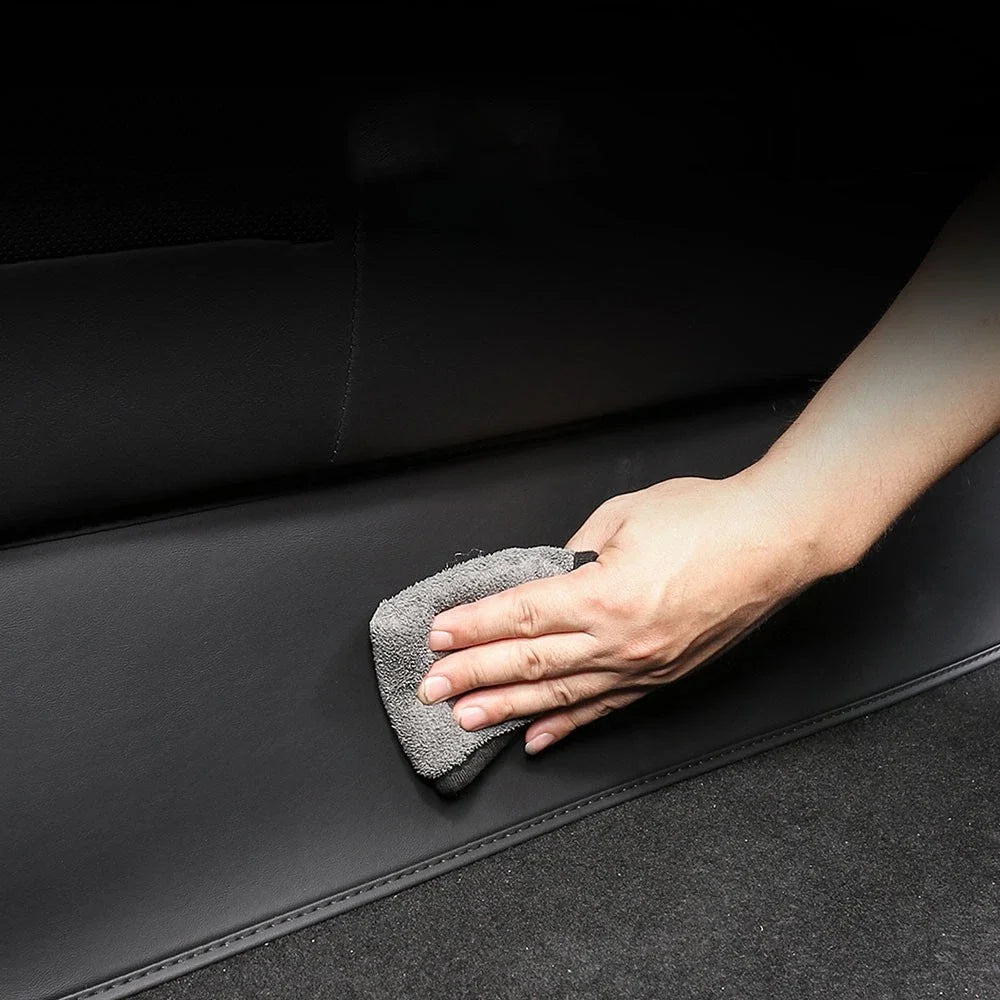 Wiping clean the waterproof faux-leather Tesla Model Y rear seat guard with a cloth