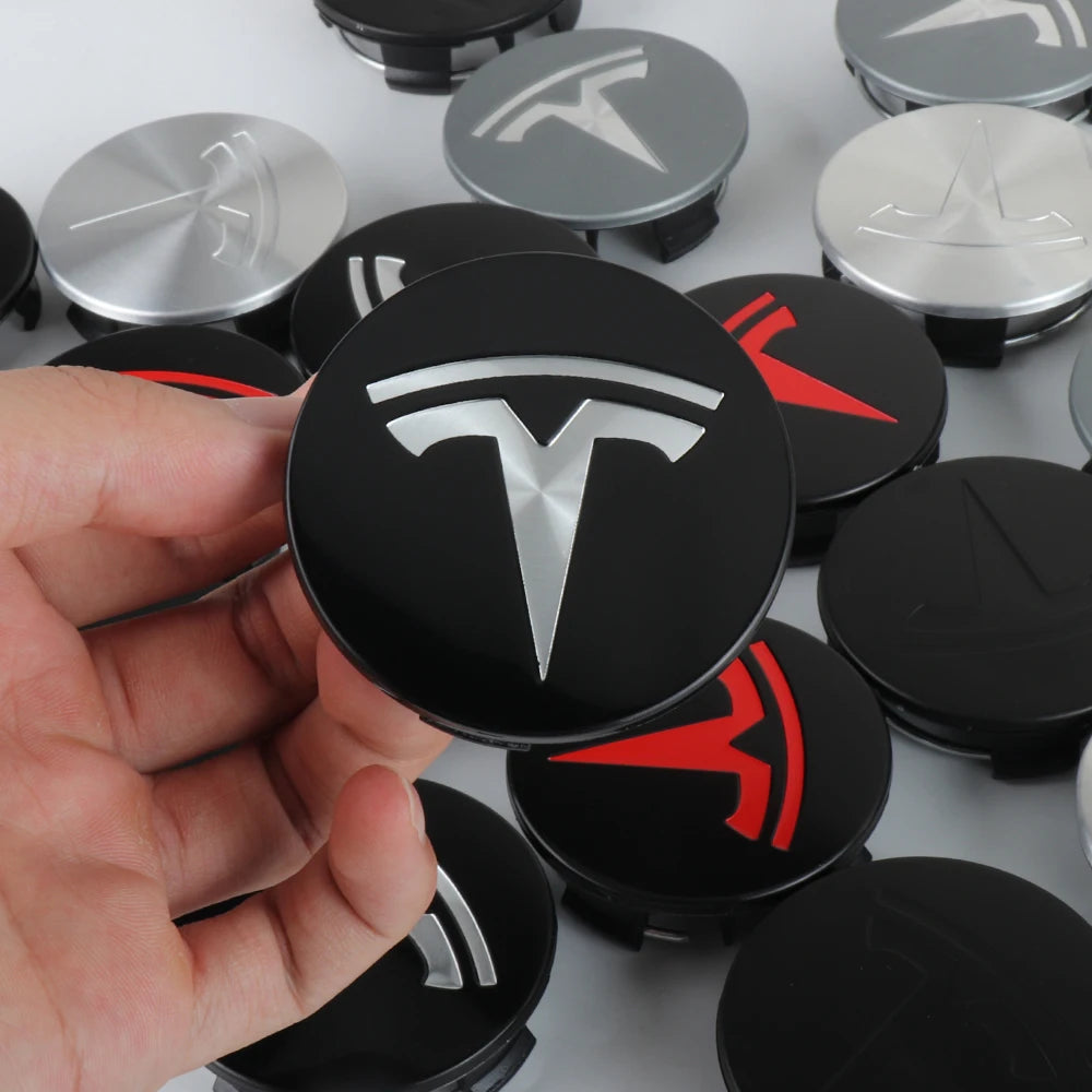 Tesla wheel center caps held in hand showing logo detail