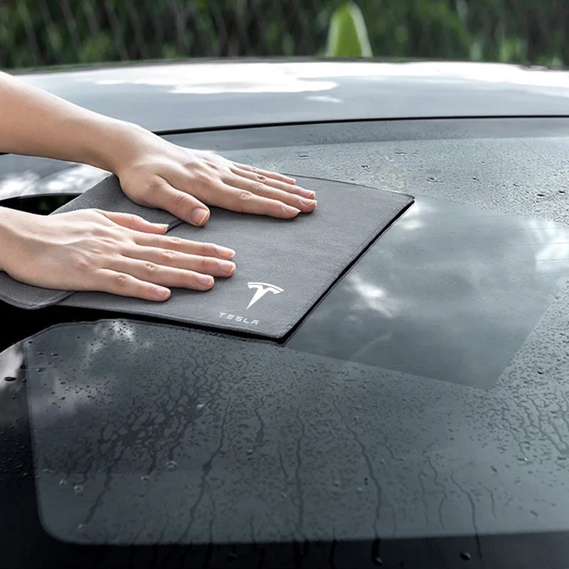 Hand drying a wet car roof with grey microfiber Tesla towel
