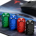 Metal Tesla tire valve stem caps in green, blue, red, and black
