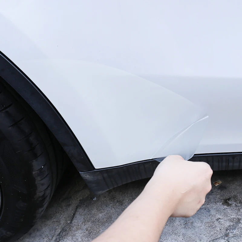 Hand applying clear TPU protective film to Tesla lower door panel