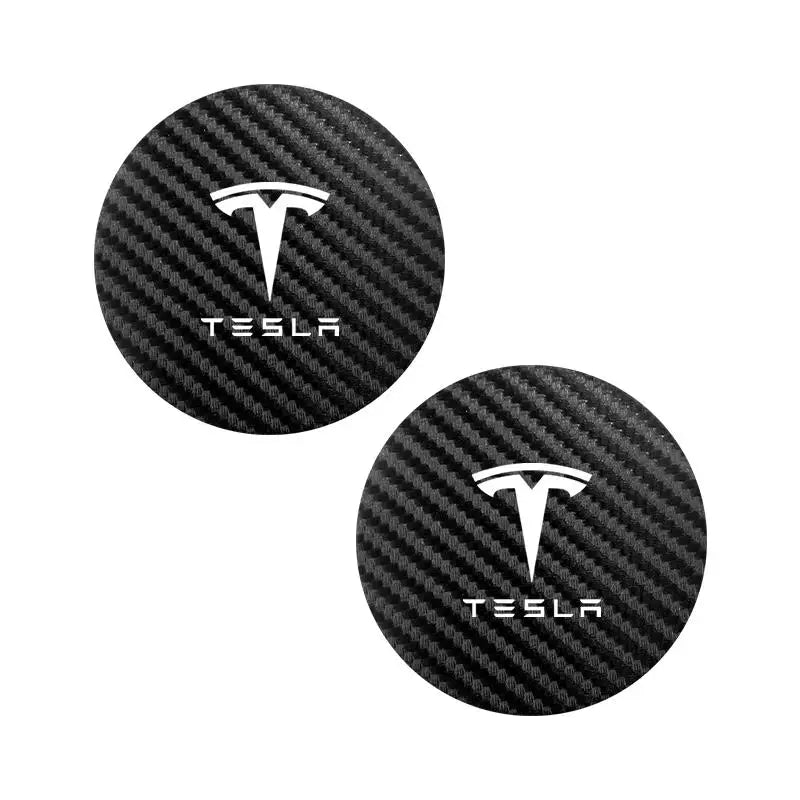 Pair of Tesla logo carbon-fiber cup holder coasters on white background