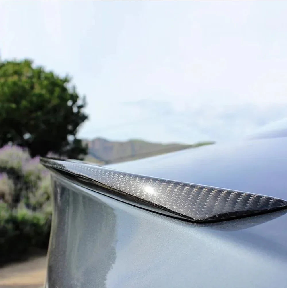 Carbon fiber car spoiler with glossy weave texture, mounted on vehicle rear for aerodynamic styling